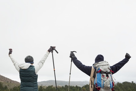 25460011-rear-view-of-a-couple-raising-hands-after-a-trek-against-clear-sky